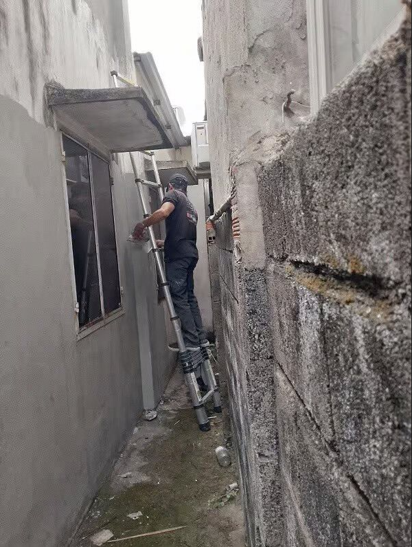 Kỹ thuật viên đang kiểm tra hệ thống chống thấm trên mái nhà hoặc tường ngoại thất, với các dụng cụ chuyên dụng, thể hiện sự tập trung vào việc bảo trì tòa nhà để tránh hư hỏng do thấm nước