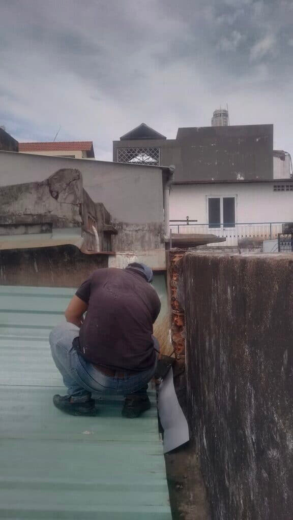 Kỹ thuật viên đang kiểm tra hệ thống thoát nước trên mái nhà hoặc sân thượng, đảm bảo các rãnh thoát nước sạch sẽ và không bị tắc nghẽn. Hình ảnh này thể hiện tầm quan trọng của việc bảo trì hệ thống thoát nước định kỳ để ngăn ngừa thấm nước và ngập úng