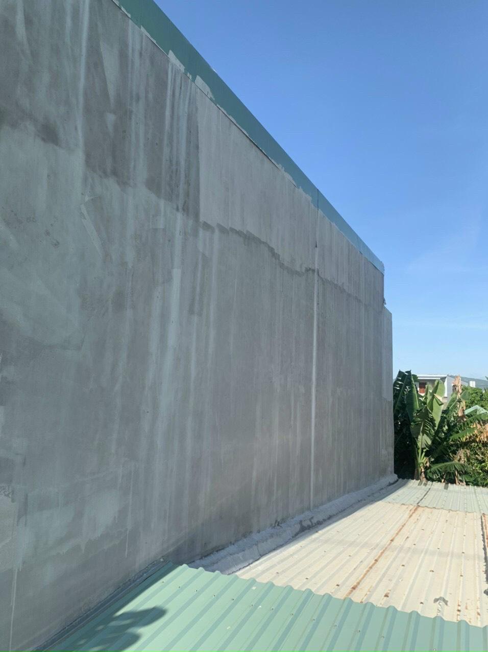 Hình ảnh một bức tường ngoài trời sau khi đã hoàn thiện quá trình chống thấm, có bề mặt mịn, sạch sẽ, không có dấu hiệu thấm nước, rêu mốc hoặc nứt nẻ. Bối cảnh của ảnh là một tòa nhà được bảo vệ hoàn hảo với môi trường xung quanh trong điều kiện thời tiết nắng hoặc mưa, thể hiện tính bền vững và hiệu quả của giải pháp chống thấm