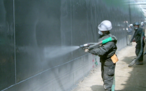 Ảnh thi công công nghệ chống thấm: Công nhân sử dụng máy phun để thi công màng chống thấm polyurea trên tường ngoài trời.