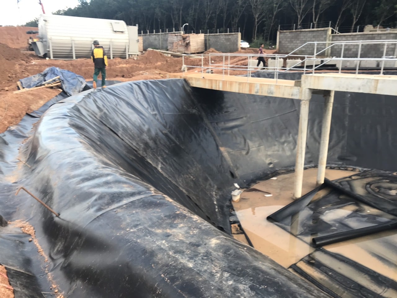 Ảnh thi công màng chống thấm HDPE: Công nhân đang trải và dán màng chống thấm HDPE lên bể nước sinh hoạt.