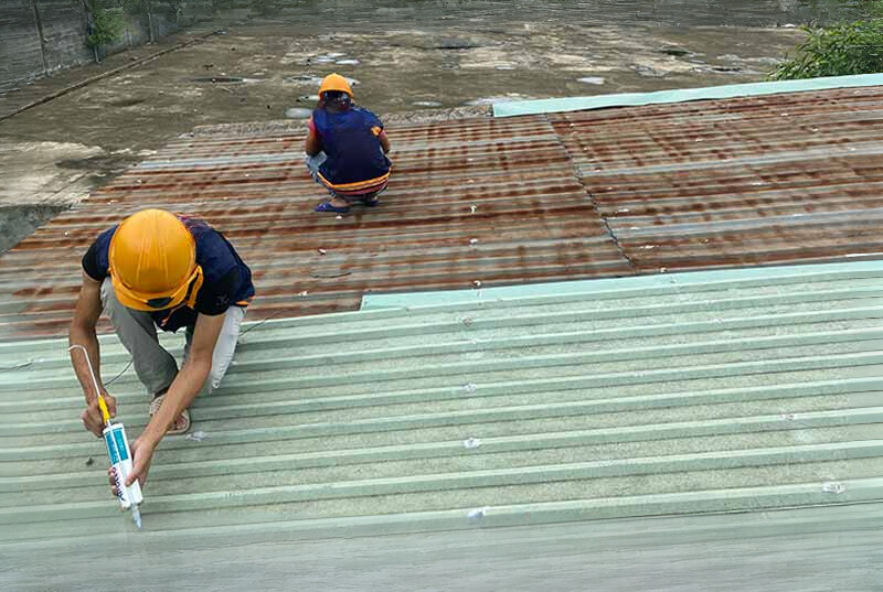 Ảnh thi công keo chống thấm PU: Kỹ thuật viên đang bơm keo chống thấm PU vào các mối nối và vết nứt trên mái tôn để ngăn nước thấm qua.