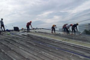 Ảnh kiểm tra và vệ sinh mái tôn nhà xưởng: Công nhân đang làm sạch mái tôn nhà xưởng bằng dụng cụ chuyên dụng, loại bỏ rêu mốc và bụi bẩn.